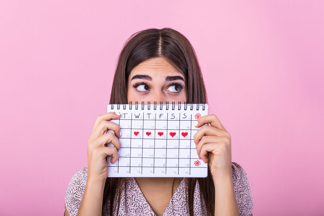 femme qui tient entre ses mains un calendrier de suivi de cycle menstruel